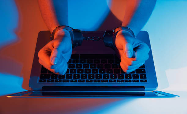 Man in handcuffs at the computer. Cyber crime concept