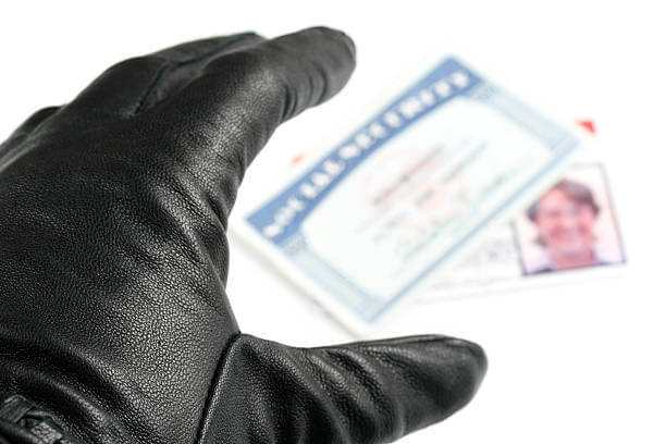 A gloved hand reaches for a social security card and id card.